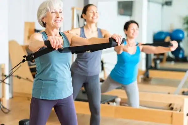 Toning Arms After 60: Empowering Womens Fitness Through Effective Weight Training 2 older woman doing weight training Southall and resistance in the gym to tone upper arms